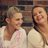 Two girls sitting on bench smiling.